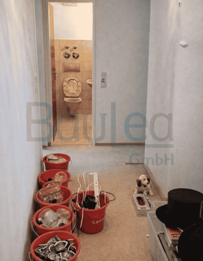 Wohnungsrenovierung München VORHER – Flur im Rohzustand, altes Bad im Hintergrund